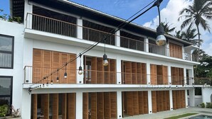 A two-story building with a swimming pool, wooden shutters, and a balcony with string lights. - Marshmallow Bay (Ahangama)
