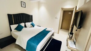 Camera d'albergo con un letto, un comodino, una TV e una porta che dà su un'altra stanza.