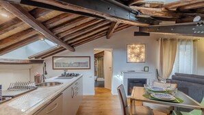 A modern kitchen with a wooden ceiling, a dining area with a fireplace, and a view of the cityscape through the window. - Elegant historic apartment, Dimora Capo di Ferro (Roma)
