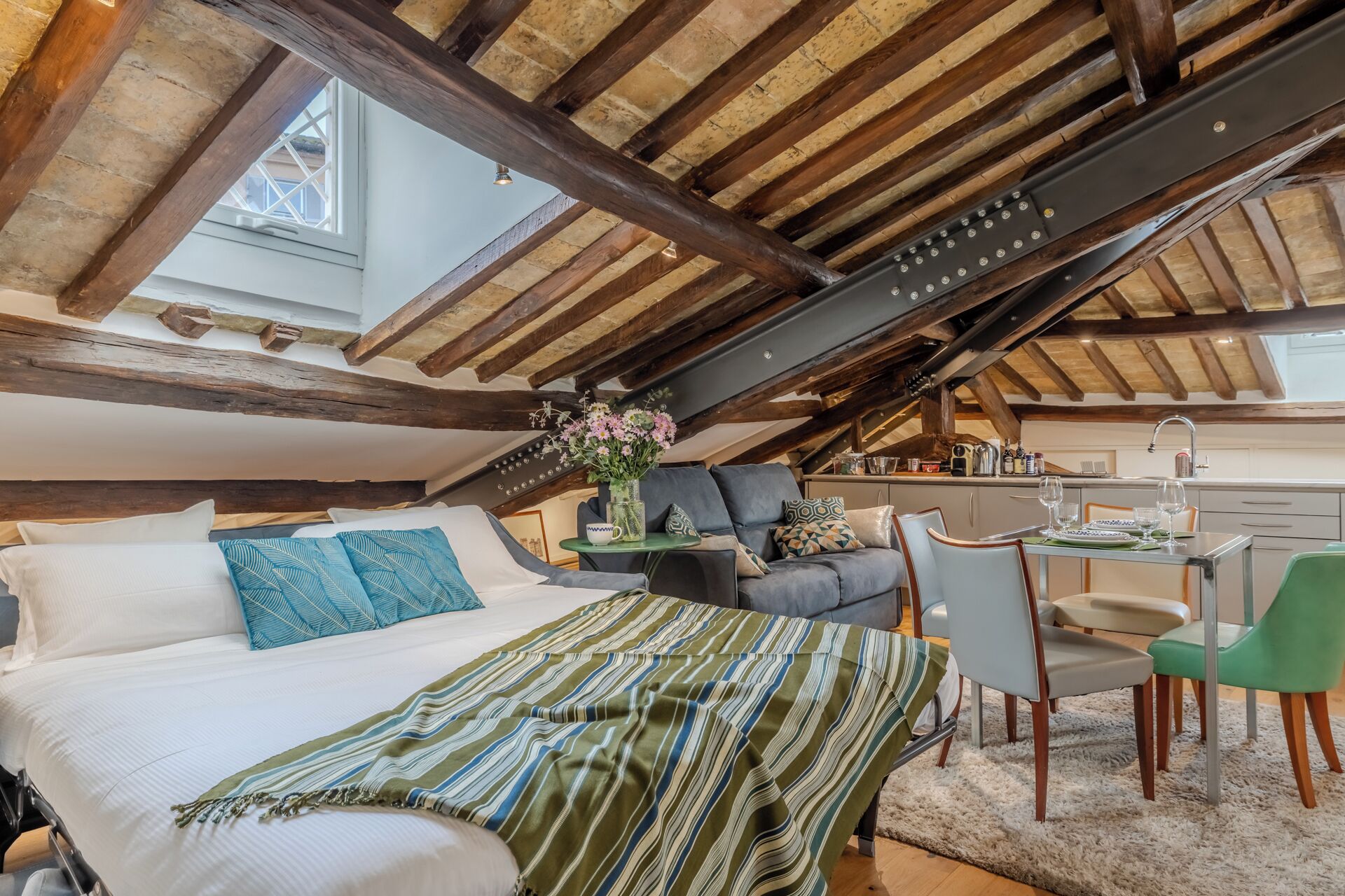 Ein gemütliches Schlafzimmer unter dem Dach mit einem großen Bett, einer Couch und einem Essbereich.