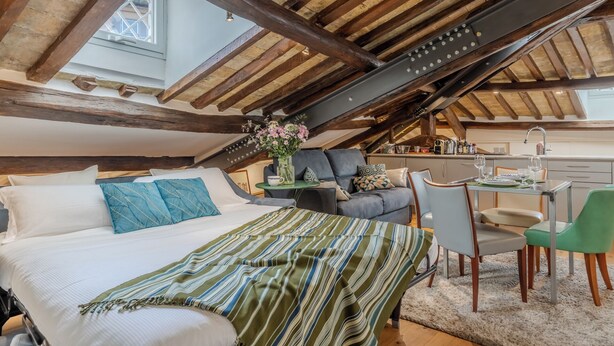 A cozy attic bedroom with a large bed, a sofa, and a dining area. - Elegant historic apartment, Dimora Capo di Ferro (Roma)