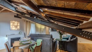 A dining area with a table set for two, a sofa, and a small side table with a vase. - Elegant historic apartment, Dimora Capo di Ferro (Roma)