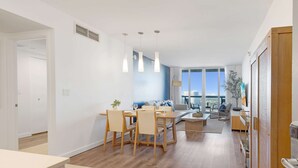 Ein modernes Wohnzimmer mit Essbereich, einer Couch, einem Couchtisch und Blick auf die Stadt.