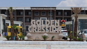 The exterior of Golden Cressida Resort & Palace with a prominent sign, palm trees, and a parking area. - GOLDEN CRESSIDA RESORT & PALACE (Mozamabad)