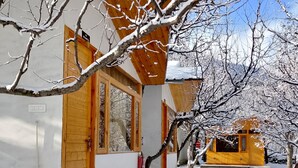 A snow-covered building with a wooden exterior and large windows. - nine Apple Resort Dharali Harsil (Bhatwari)