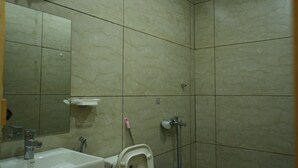 A bathroom with a toilet, sink, mirror, and a blue bucket. - nine Apple Resort Dharali Harsil (Bhatwari)