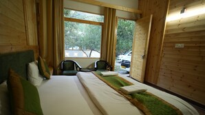 A room with a large bed, two chairs, a window with a view of trees and parked cars, and wooden walls. - nine Apple Resort Dharali Harsil (Bhatwari)