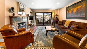 A spacious living room with leather furniture, a fireplace, and a large window offering a scenic view.