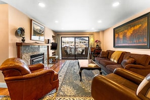 A spacious living room with leather furniture, a fireplace, and a large window offering a scenic view.