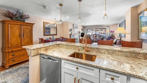 A modern kitchen with granite countertops, stainless steel appliances, and pendant lighting.