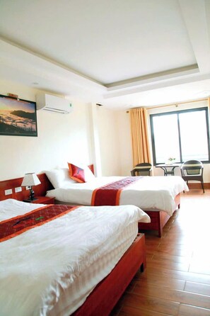 A hotel room with two beds, a window with curtains, a table with chairs, and a painting on the wall. - Son Ha Hotel Sapa (Sa Pa)
