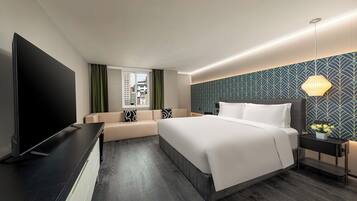 Habitación de hotel moderna con una cama grande, televisión de pantalla plana, zona de estar y vista a la ciudad.