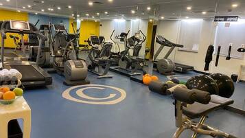 A gym with various cardio machines, weightlifting equipment, and a mirrored wall.
