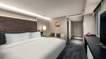 Een moderne hotelkamer met een groot bed, een flatscreen televisie, een bureau en een zithoek.