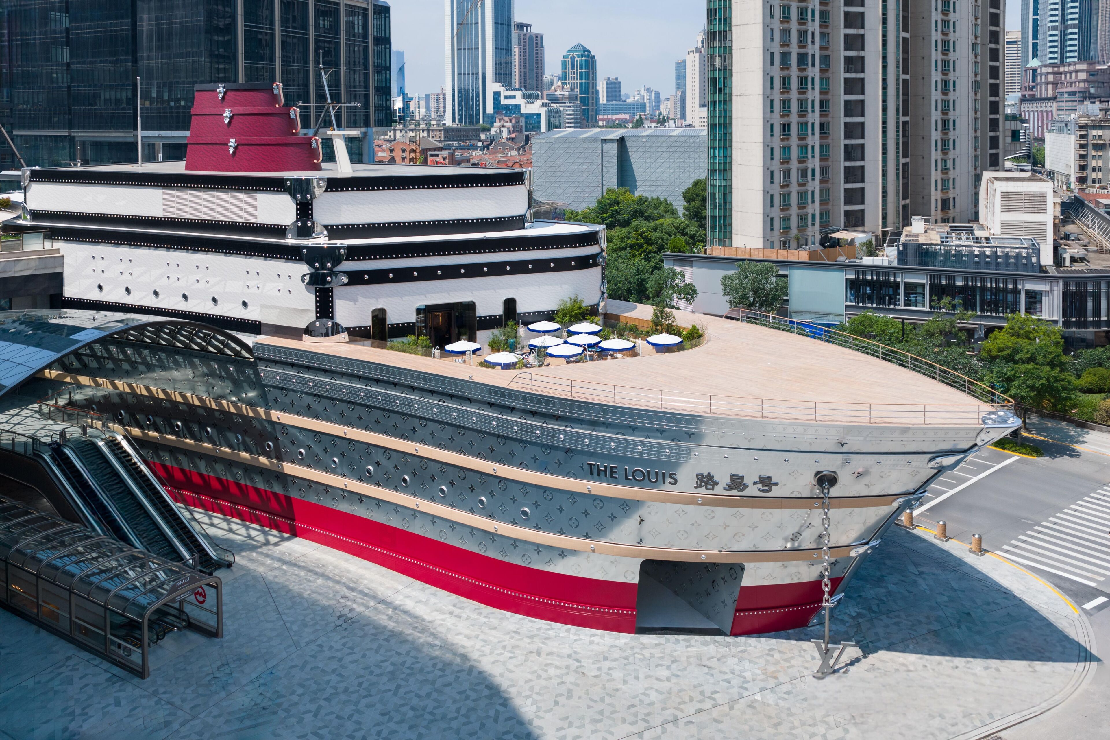 Ein großes Kreuzfahrtschiff liegt an einem Hafen, nebenan ein modernes Gebäude.