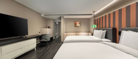 Een hotelkamer met een grote flatscreen-tv, een bureau met stoel, twee bedden en een gestreepte wand.