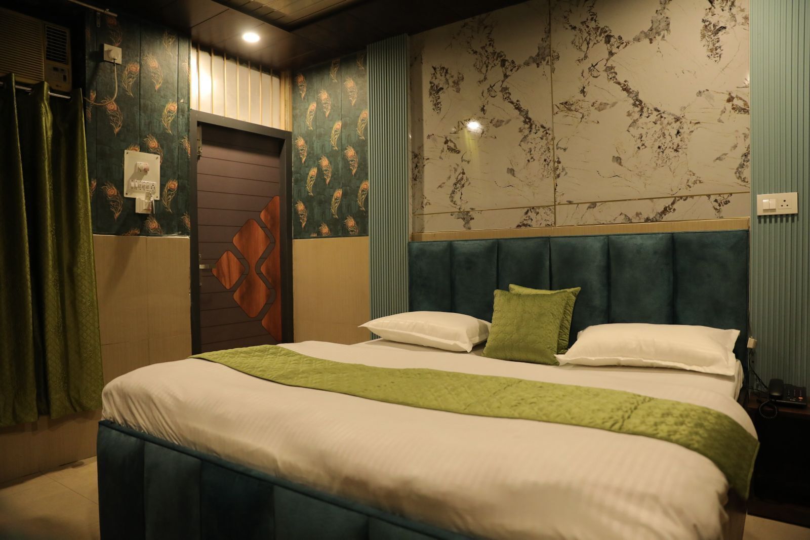 Habitación de hotel con cama, cabecera, pared con estampado floral y puerta de diseño geométrico.