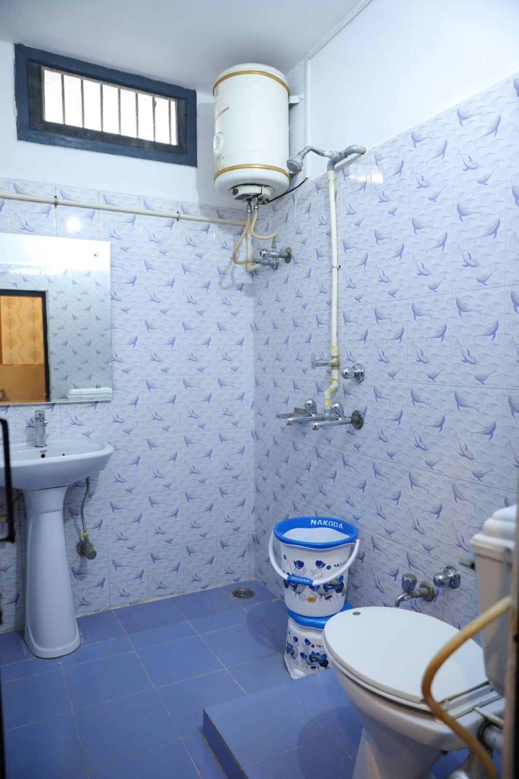 A bathroom with a toilet, bidet, sink, and a water heater.