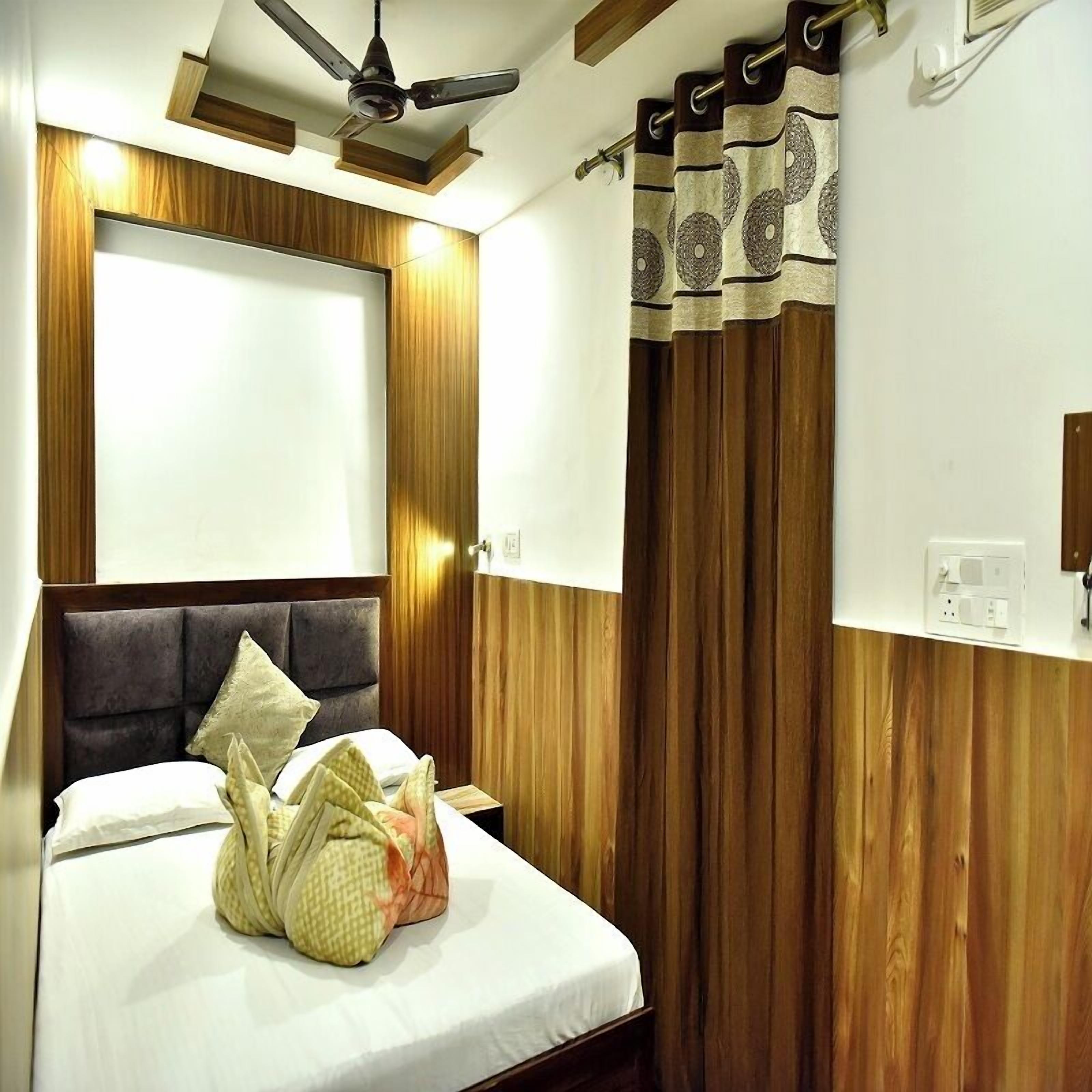 Un dormitorio con cama, paneles de madera, ventilador de techo y ventana con cortinas.