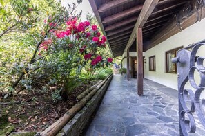 A stone pathway leading to a building with a wooden ceiling and windows.
