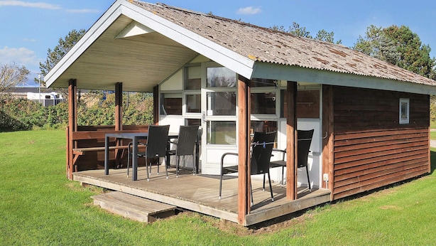 A small wooden cabin with a covered porch and a dining area. - 5 Star Holiday Home in Lokken (Lokken)