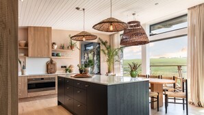 Una cocina moderna con una isla grande, armarios de madera y vistas al campo.