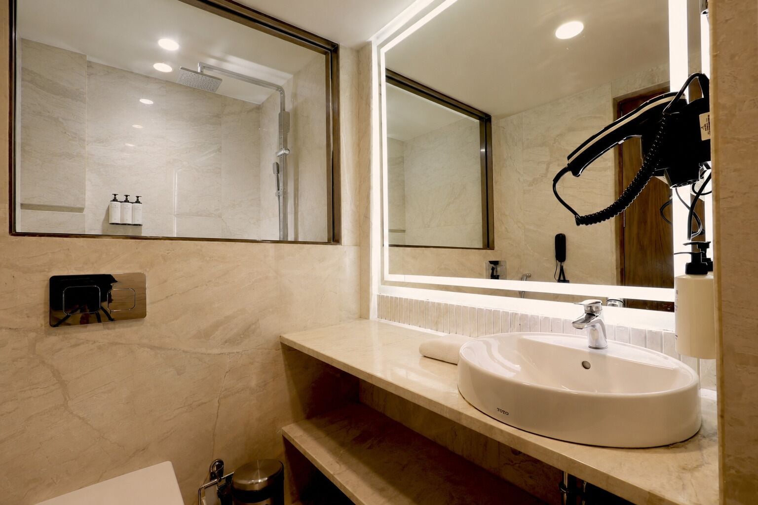 A modern bathroom with a large mirror, a white sink, and a shower area.