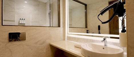 A modern bathroom with a large mirror, a white sink, and a shower area.