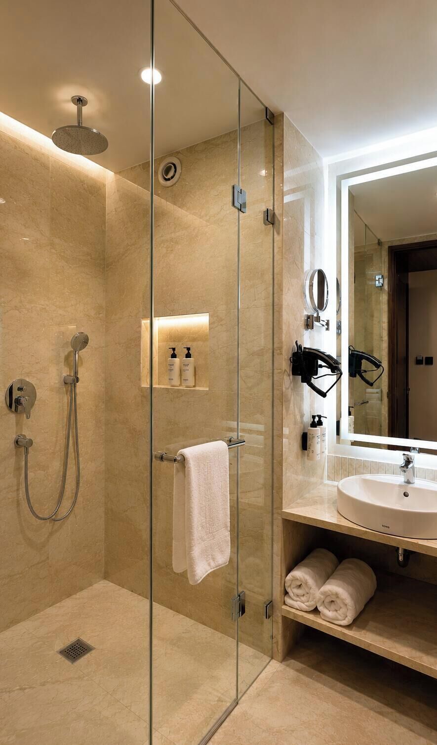A modern bathroom with a glass-enclosed shower, a sink, and a mirror.