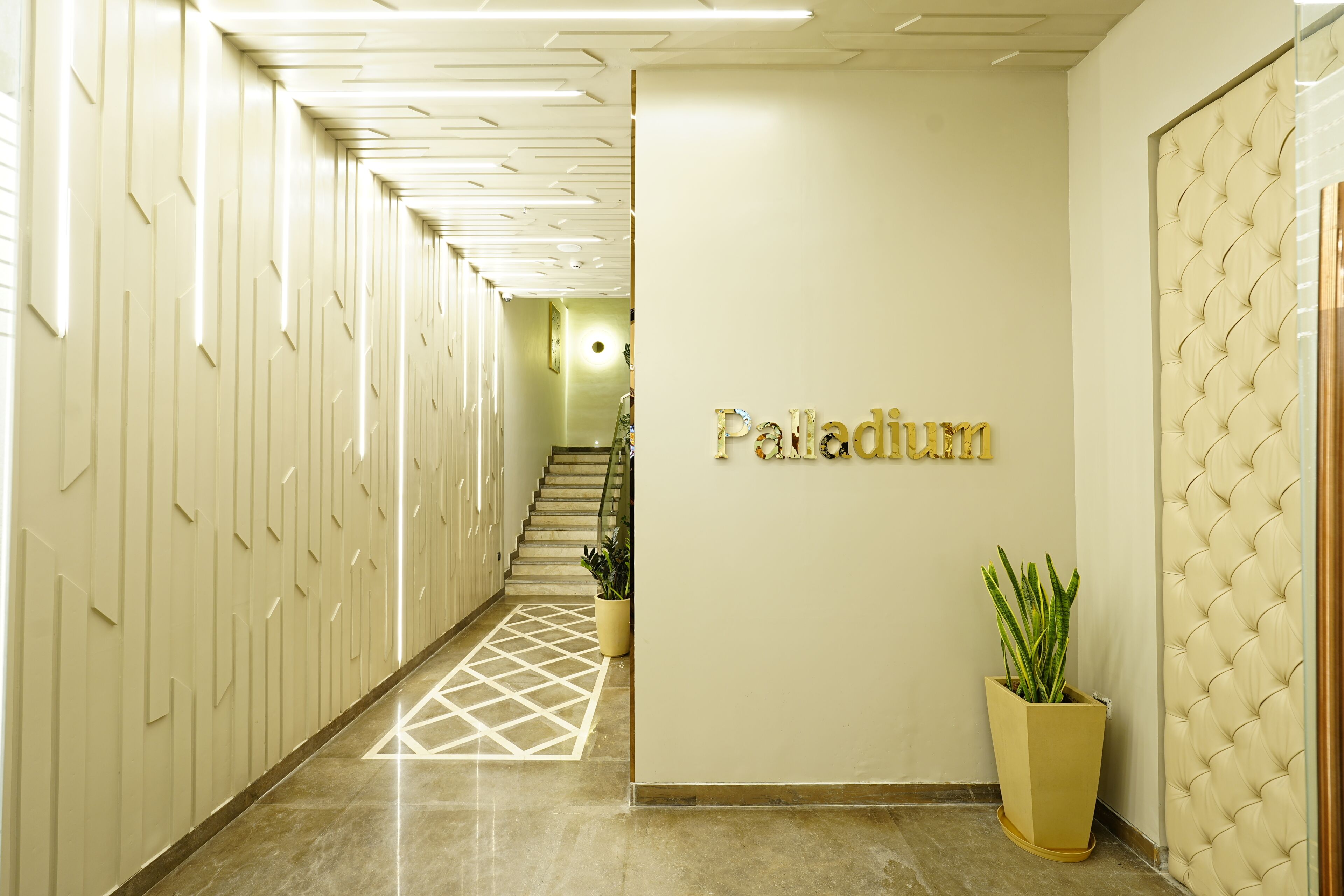 Un pasillo con suelo de diseño geométrico, un mostrador de recepción con la palabra 'Paladium' en la pared y una planta en maceta.