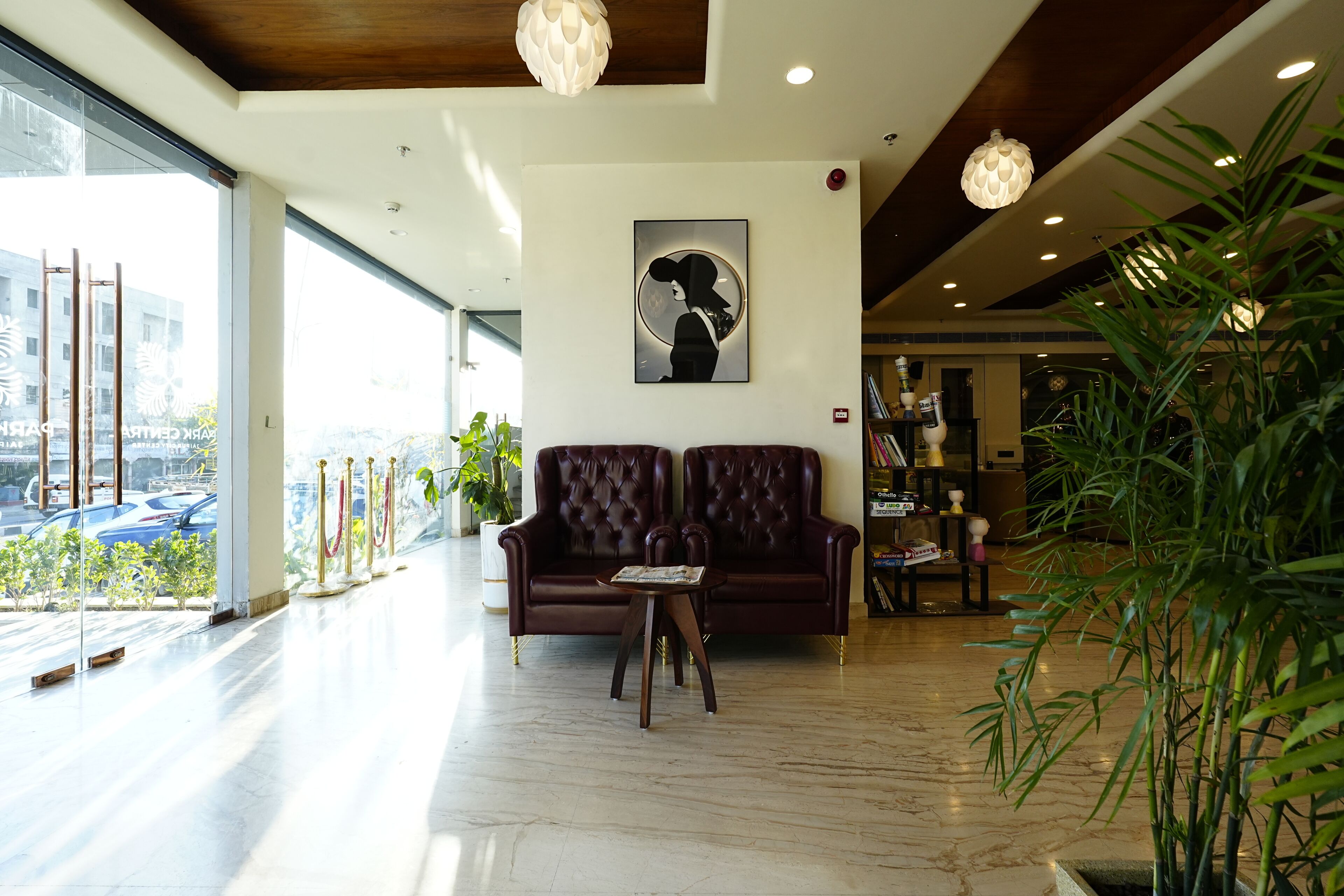 A lobby with a leather sofa, a coffee table, a large window, and a potted plant.