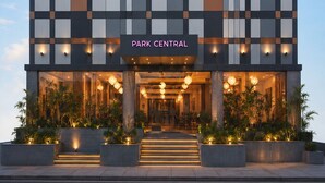 Un bâtiment moderne à la façade à motifs géométriques, doté d’une entrée centrale et d’une enseigne indiquant « PARK CENTRAL ».