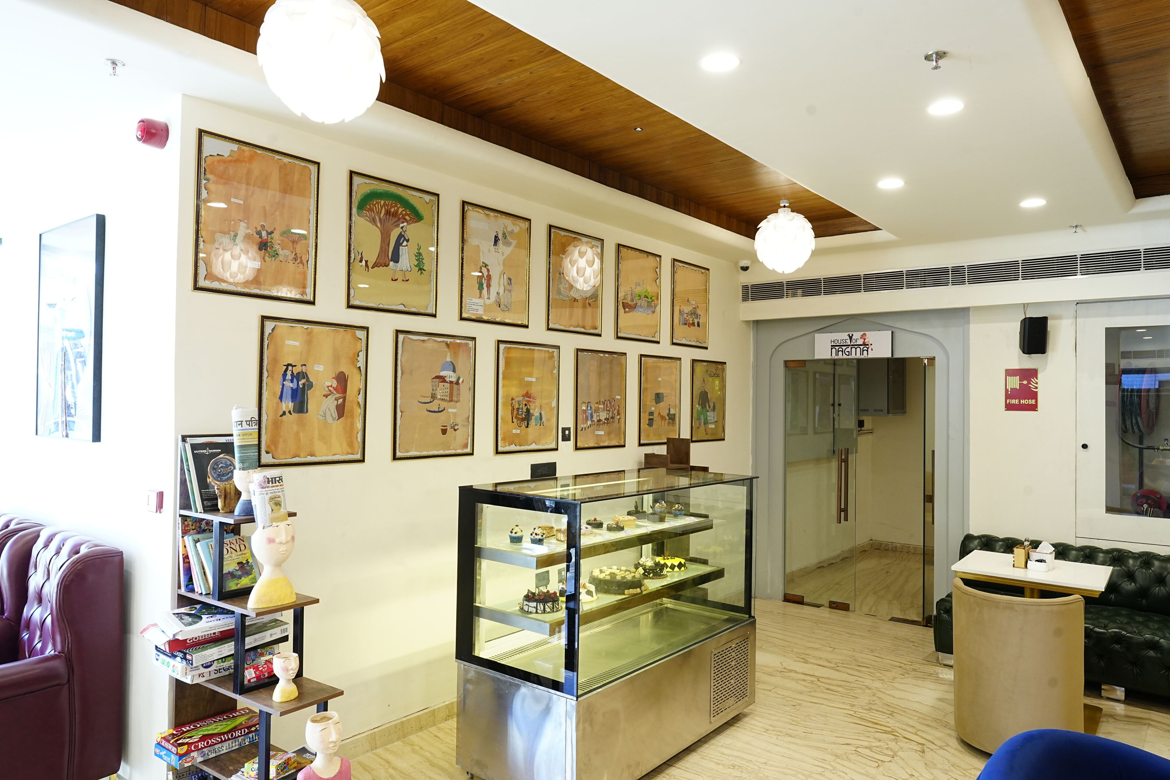 Um quarto com uma vitrine de vidro, estantes de livros, um sofá e obras de arte emolduradas nas paredes.