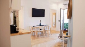 A modern dining area with a wooden table and chairs, a flat-screen TV mounted on the wall, and a large mirror on the wall. - *Bright 2-Room Apartment for friends and relatives*10 MINUTES FROM THE CATHEDRAL (Milano)