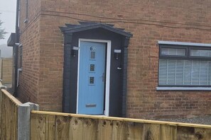 A blue door with the number 66, a small porch, and a window with shutters. - Chester - 4 Bed House Free Parking (Chester)