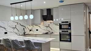 A modern kitchen with a skylight, marble countertop, and built-in appliances. - Chester - 4 Bed House Free Parking (Chester)