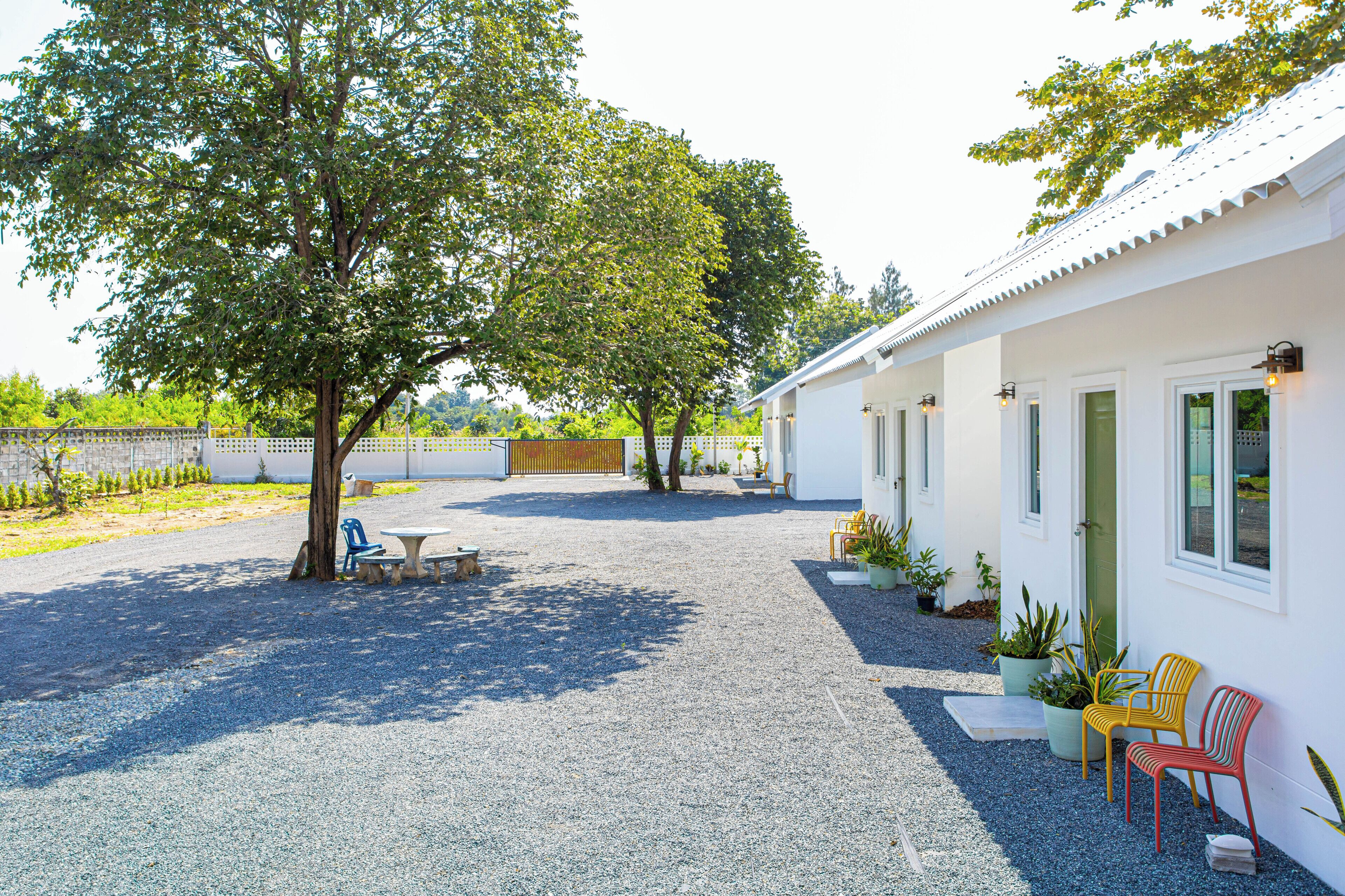 A building with a gravel driveway, outdoor seating, and potted plants.