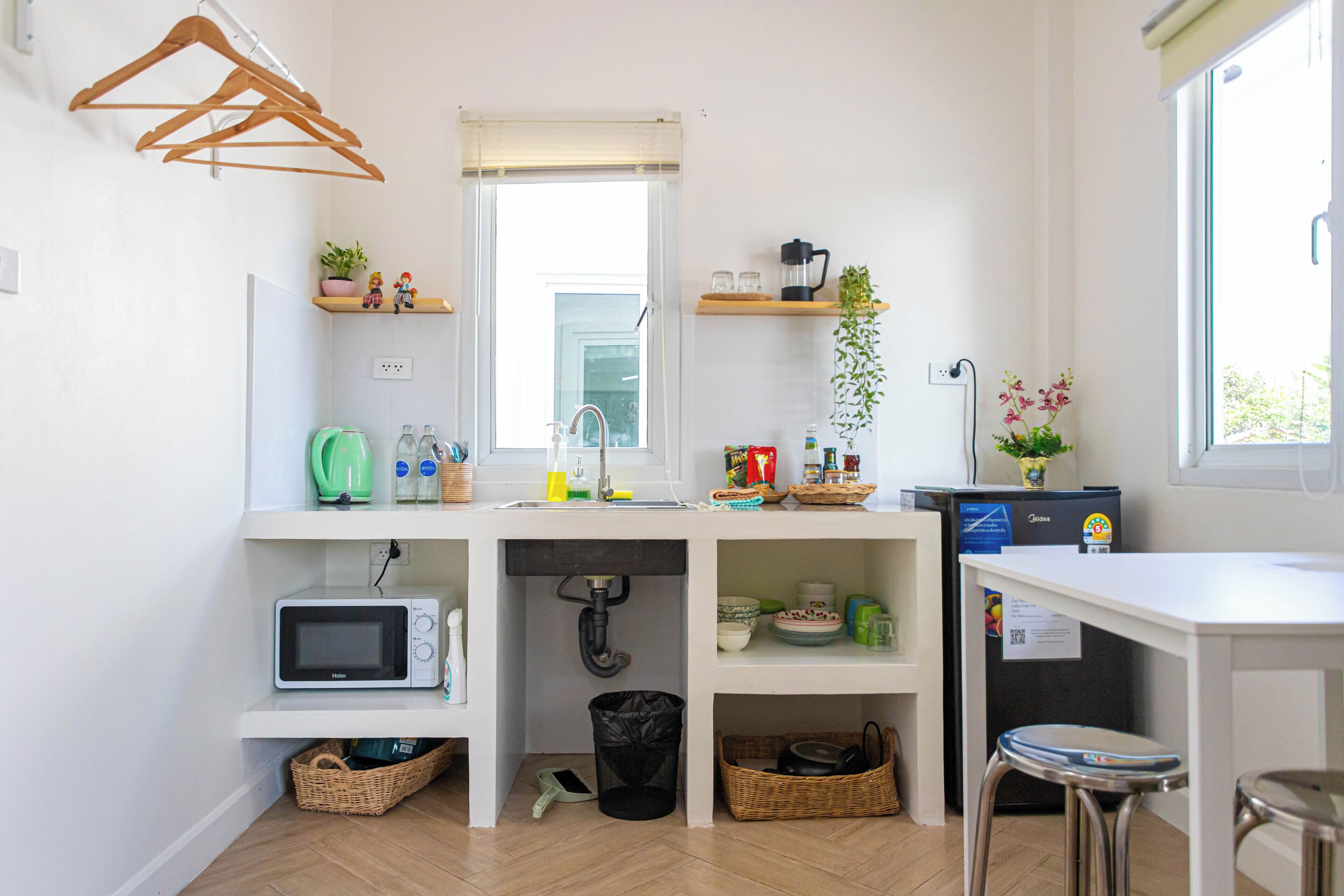 A compact kitchen with a microwave, sink, and various storage baskets.