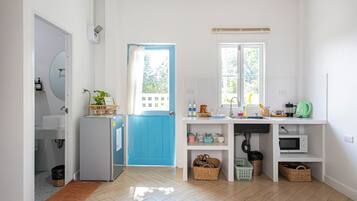 A bright kitchen with a blue door, white cabinets, and a window.