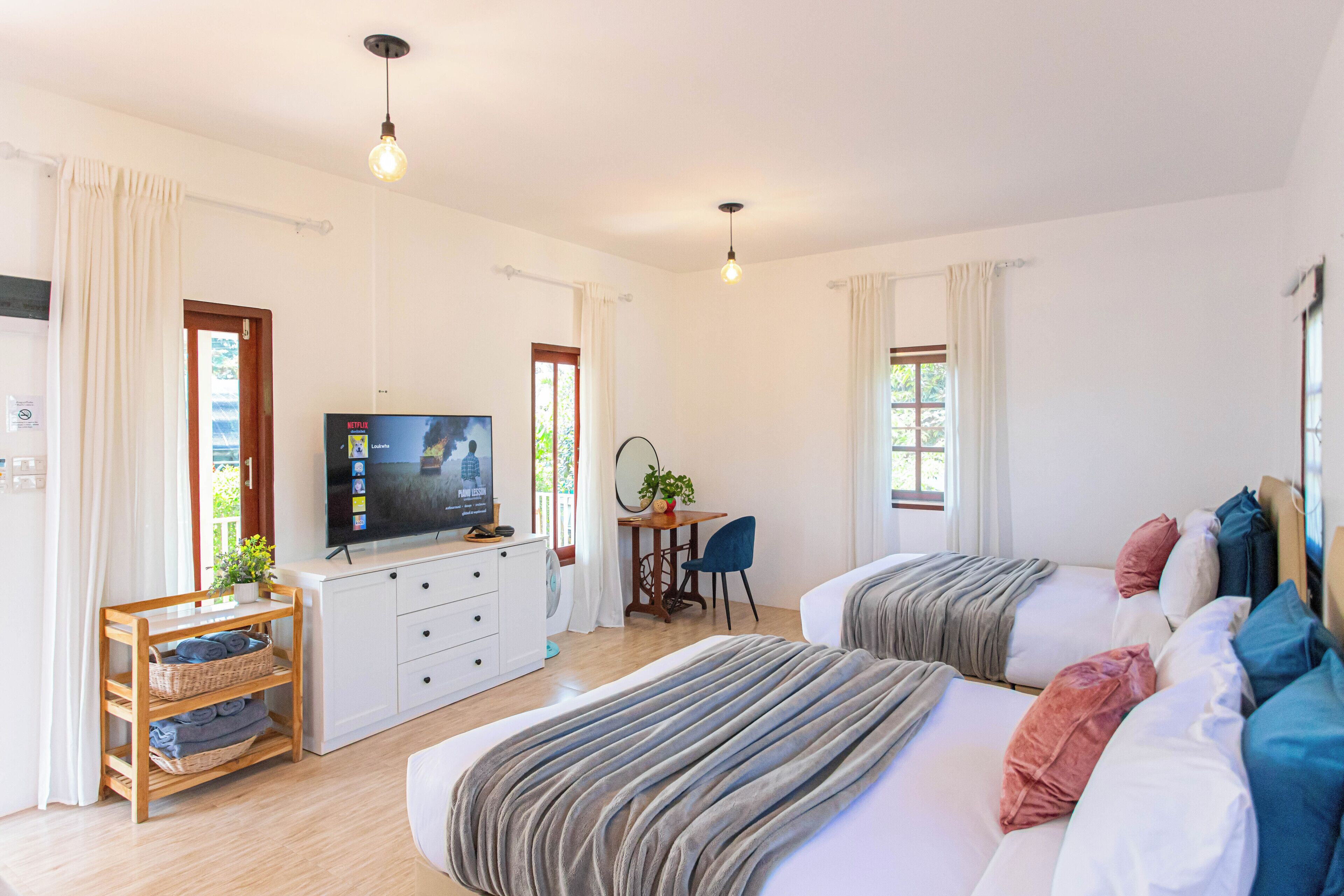 A modern hotel room with two beds, a TV, a desk, and a plant.