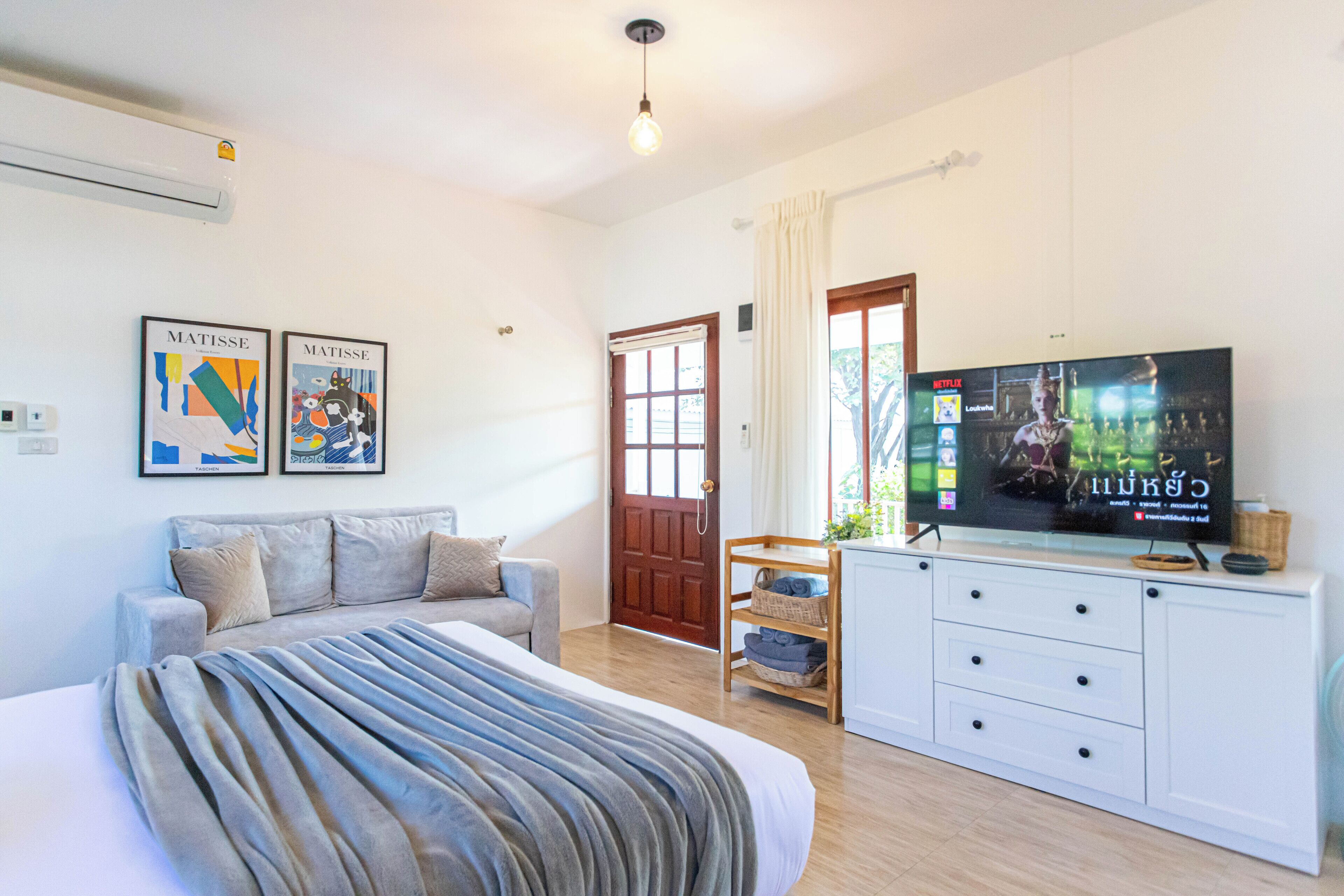 A bedroom with a bed, a TV, a sofa, and a dresser.