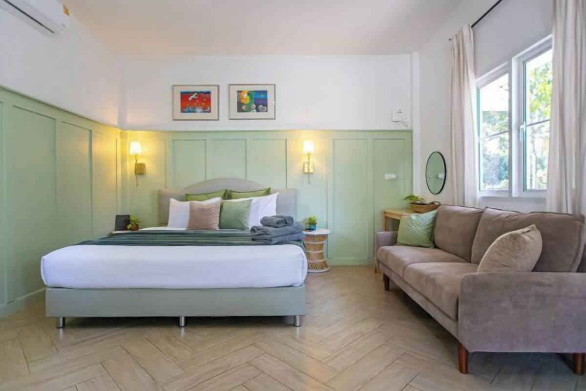 Een slaapkamer met een bed, een bank, een nachtkastje en een raam.