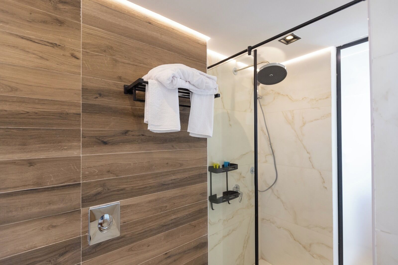 Un bagno moderno con parete in legno, box doccia in vetro e porta asciugamani con un asciugamano bianco.