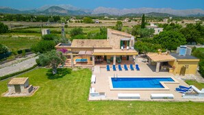 A large house with a swimming pool, outdoor seating, and a view of the mountains.