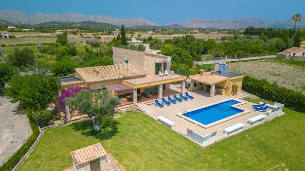 A Mediterranean-style villa with a swimming pool, outdoor seating, and a view of the surrounding landscape.