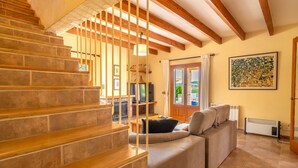 A staircase with wooden beams, a beige sofa, and a painting on the wall.