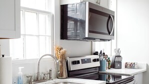 A modern kitchen with white cabinets, stainless steel appliances, and a window with natural light.