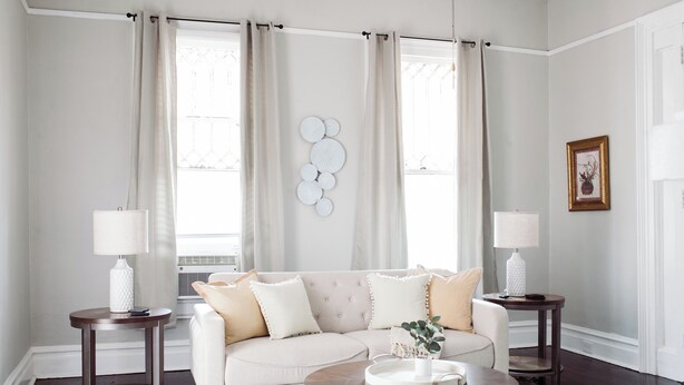 A living room with a beige sofa, two side tables, a coffee table, and a patterned rug.