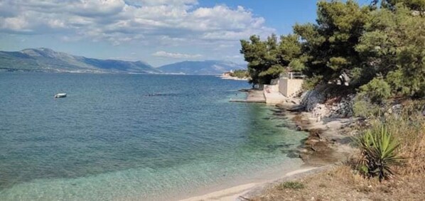A coastal landscape with clear water, a sandy beach, and trees. - Spacious cosy villa, sea view, close to the beach, airport and Trogir (Mastrinka)