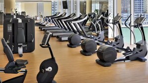 Een sportschool met meerdere loopbanden, hometrainers en roeapparaten.